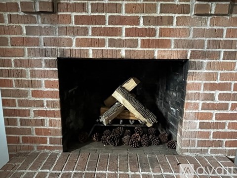 A fireplace with a pile of wood and logs inside.