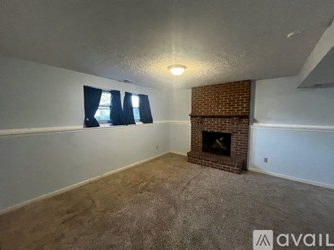 A room with a fireplace and a window with blue curtains.