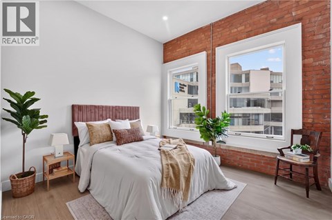 A bedroom with a large bed and a window overlooking a building.