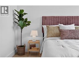 A bedroom with a bed, a lamp, a plant, and a basket.