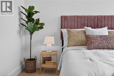 A bedroom with a bed, a lamp, a plant, and a basket.