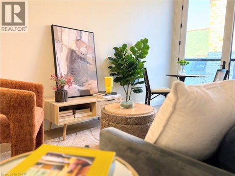 A living room with a grey couch, a brown chair, a wooden coffee table with a vase and a plant on it, and a framed picture on the wall.