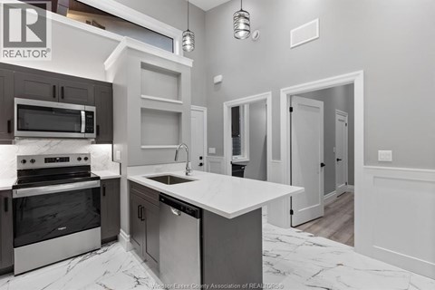 A modern kitchen with a marble countertop and stainless steel appliances.
