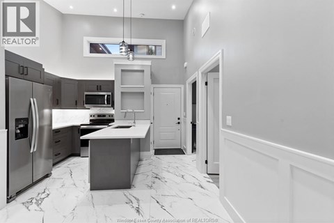 A modern kitchen with a marble floor and a refrigerator on the left.