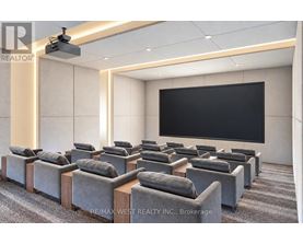 A room with grey sofas and a black screen on the wall.