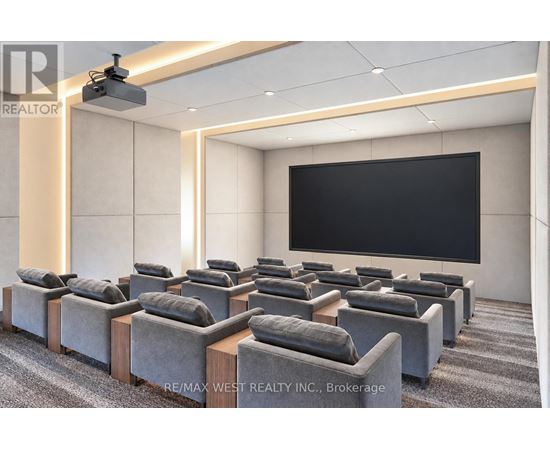A room with grey sofas and a black screen on the wall.