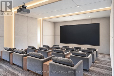 A room with grey sofas and a black screen on the wall.