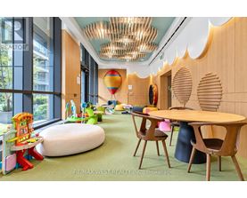 A room with a wooden table and chairs, a green carpet, and a colorful play area with a slide.
