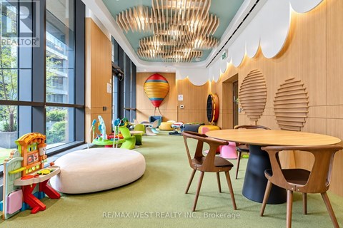 A room with a wooden table and chairs, a green carpet, and a colorful play area with a slide.