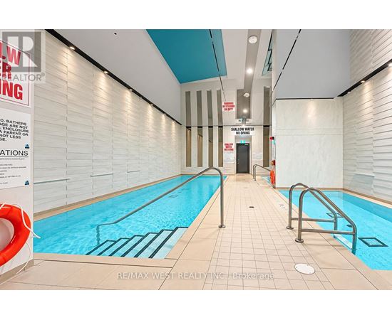 A swimming pool in a building with a sign that says "RE/MAX WEST REALTY INC. brokerage.".