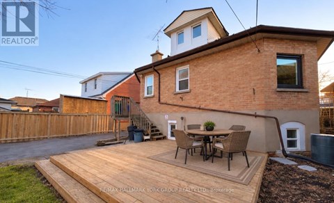 A house with a brown brick exterior and a wooden deck in front.