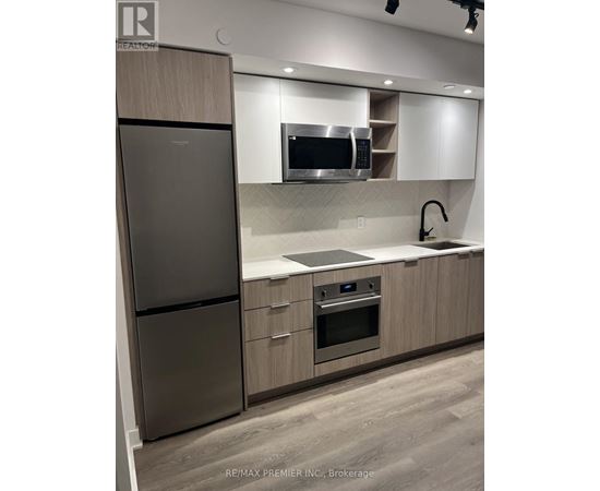 A modern kitchen with a stainless steel refrigerator and oven.