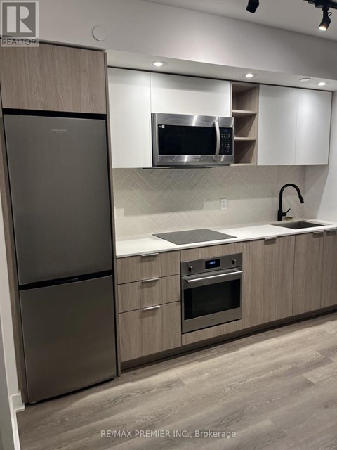 A modern kitchen with a stainless steel refrigerator and oven.