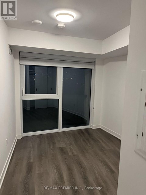 A room with a sliding glass door and wooden flooring.