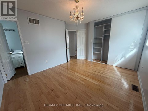 A large empty room with wooden floors and a chandelier.