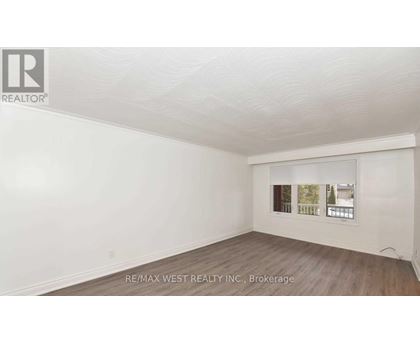 A white room with a window showing a view of trees and a building.