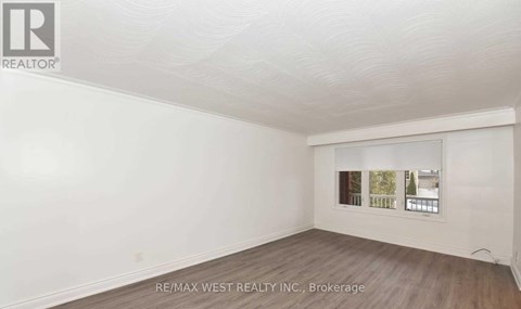 A white room with a window showing a view of trees and a building.