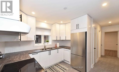 A modern kitchen with white cabinets and a stainless steel refrigerator.