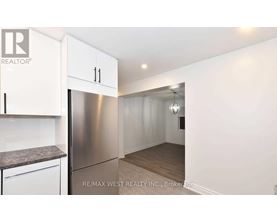 A kitchen with white cabinets and a stainless steel refrigerator.