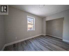 A room with a window and a wooden floor.