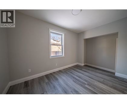 A room with a window and a wooden floor.