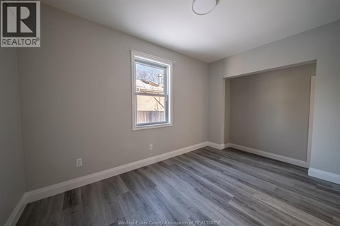 A room with a window and a wooden floor.