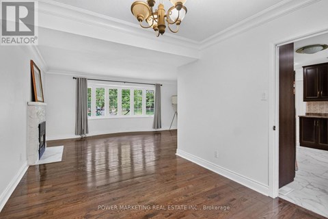 A room with a chandelier, a painting, and a window with a view of trees.