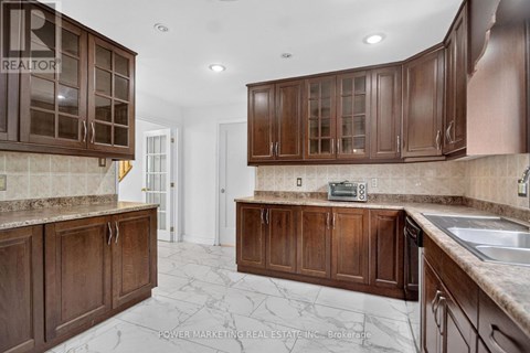 A kitchen with brown cabinets and a marble floor.