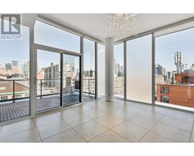A large, empty room with a view of the cityscape outside the floor-to-ceiling windows.