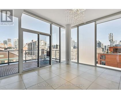 A large, empty room with a view of the cityscape outside the floor-to-ceiling windows.