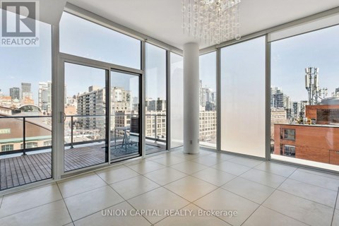 A large, empty room with a view of the cityscape outside the floor-to-ceiling windows.