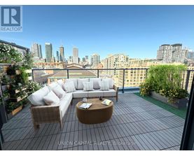 A patio with a couch, chairs and a table with a view of the city.
