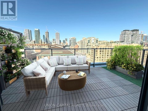 A patio with a couch, chairs and a table with a view of the city.