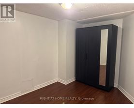 A room with a black wardrobe and wooden floor.