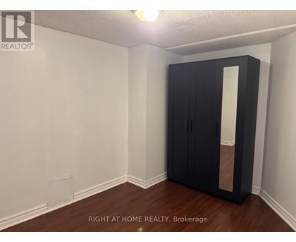 A room with a black wardrobe and wooden floor.
