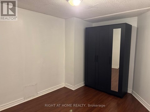 A room with a black wardrobe and wooden floor.
