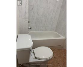 A white toilet sits next to a white bathtub in a bathroom.