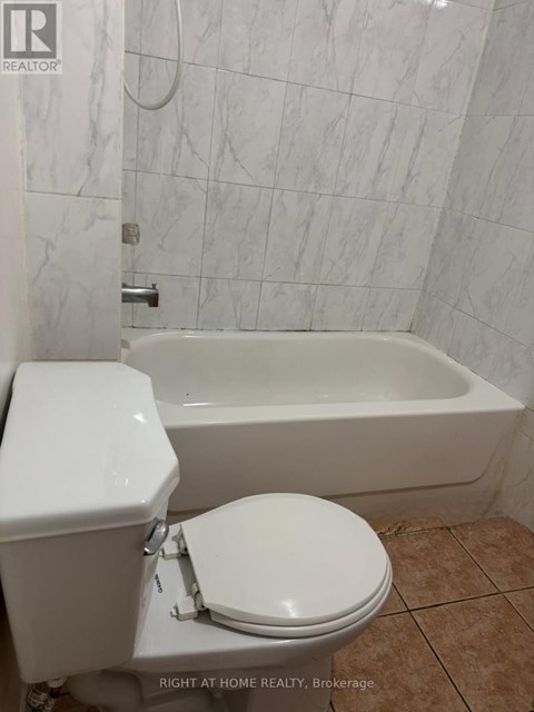 A white toilet sits next to a white bathtub in a bathroom.