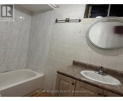 A bathroom with a tub, sink, and mirror.
