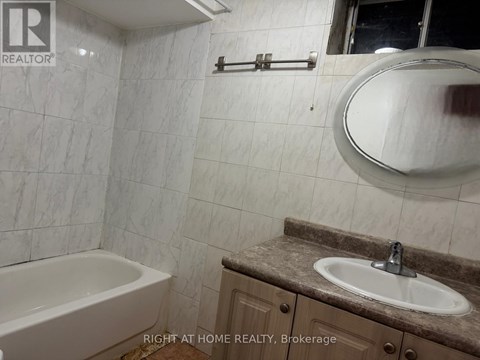 A bathroom with a tub, sink, and mirror.
