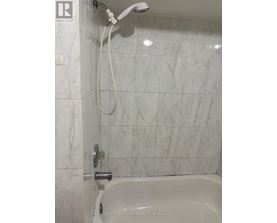 A white bathroom with a marble tile wall.