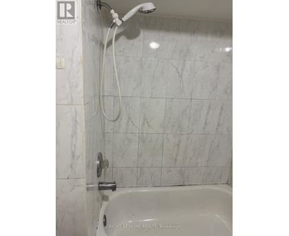 A white bathroom with a marble tile wall.