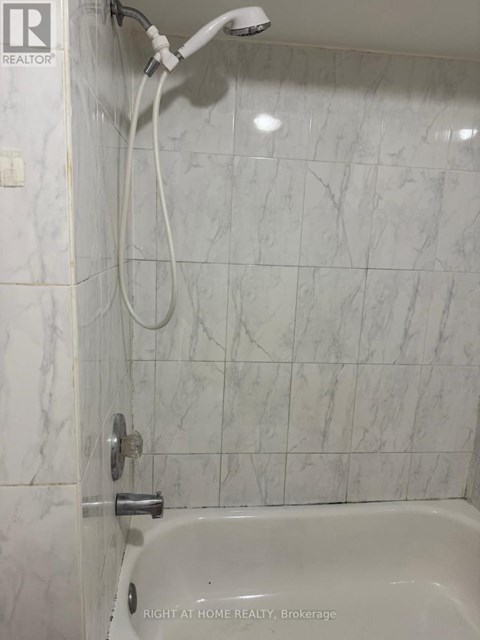 A white bathroom with a marble tile wall.