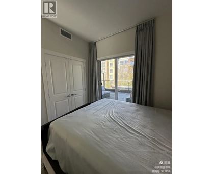 A bedroom with a large bed and a window overlooking a city.
