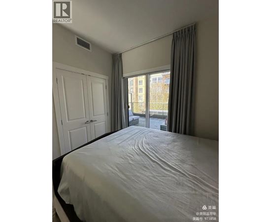 A bedroom with a large bed and a window overlooking a city.