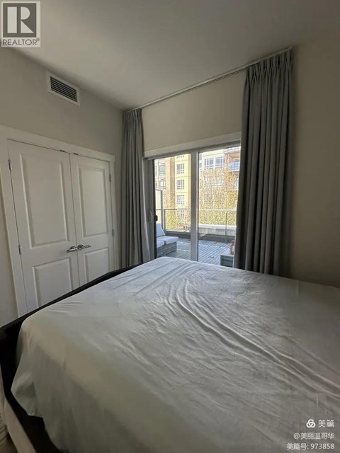 A bedroom with a large bed and a window overlooking a city.