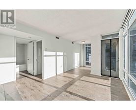 A spacious room with wooden flooring and white walls, featuring a sliding glass door.
