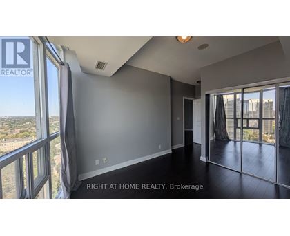 A spacious room with a view of the cityscape through large windows.