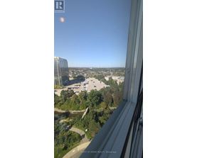 A view from a high-rise building looking out over a parking lot and trees.