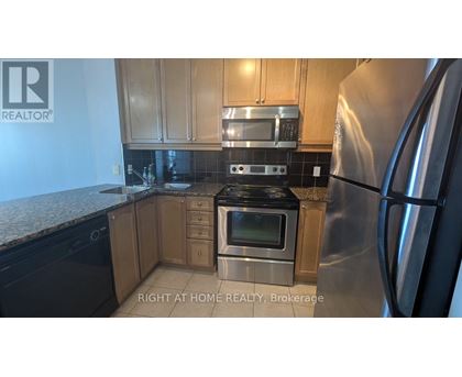 A kitchen with a stainless steel refrigerator and black countertops.